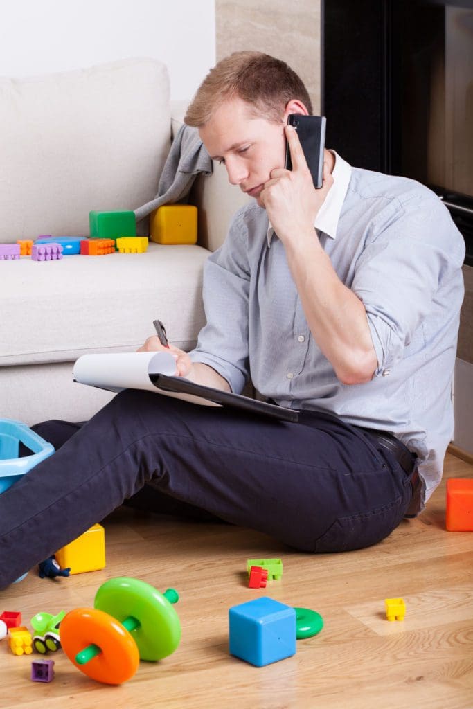 A man on the phone writing on a pad with children’s blocks around him